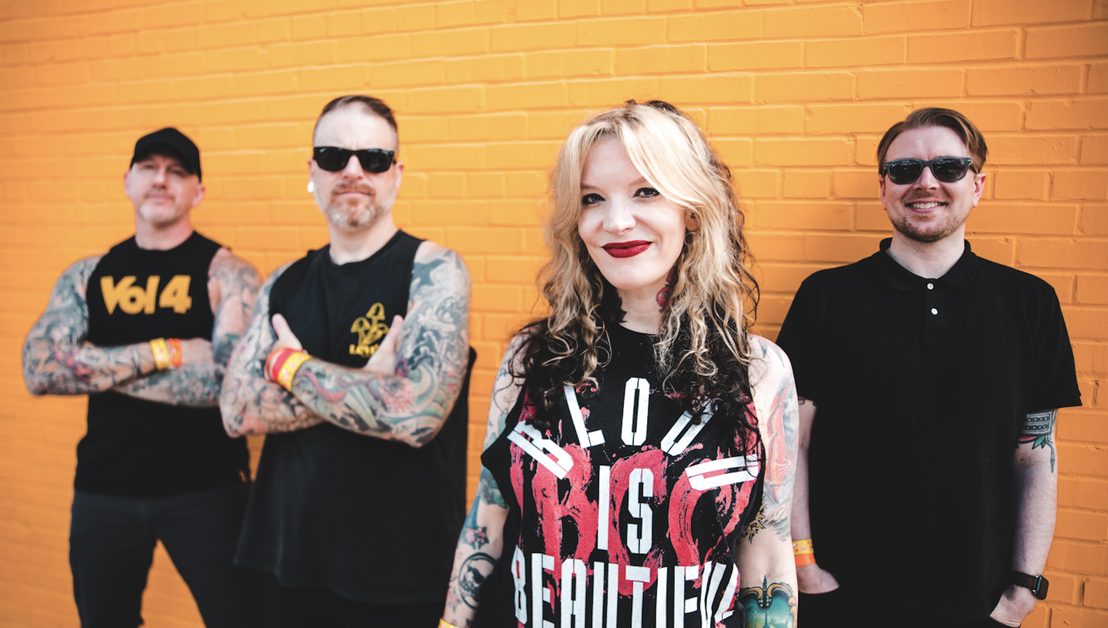 Band members standing against yellow brick wall